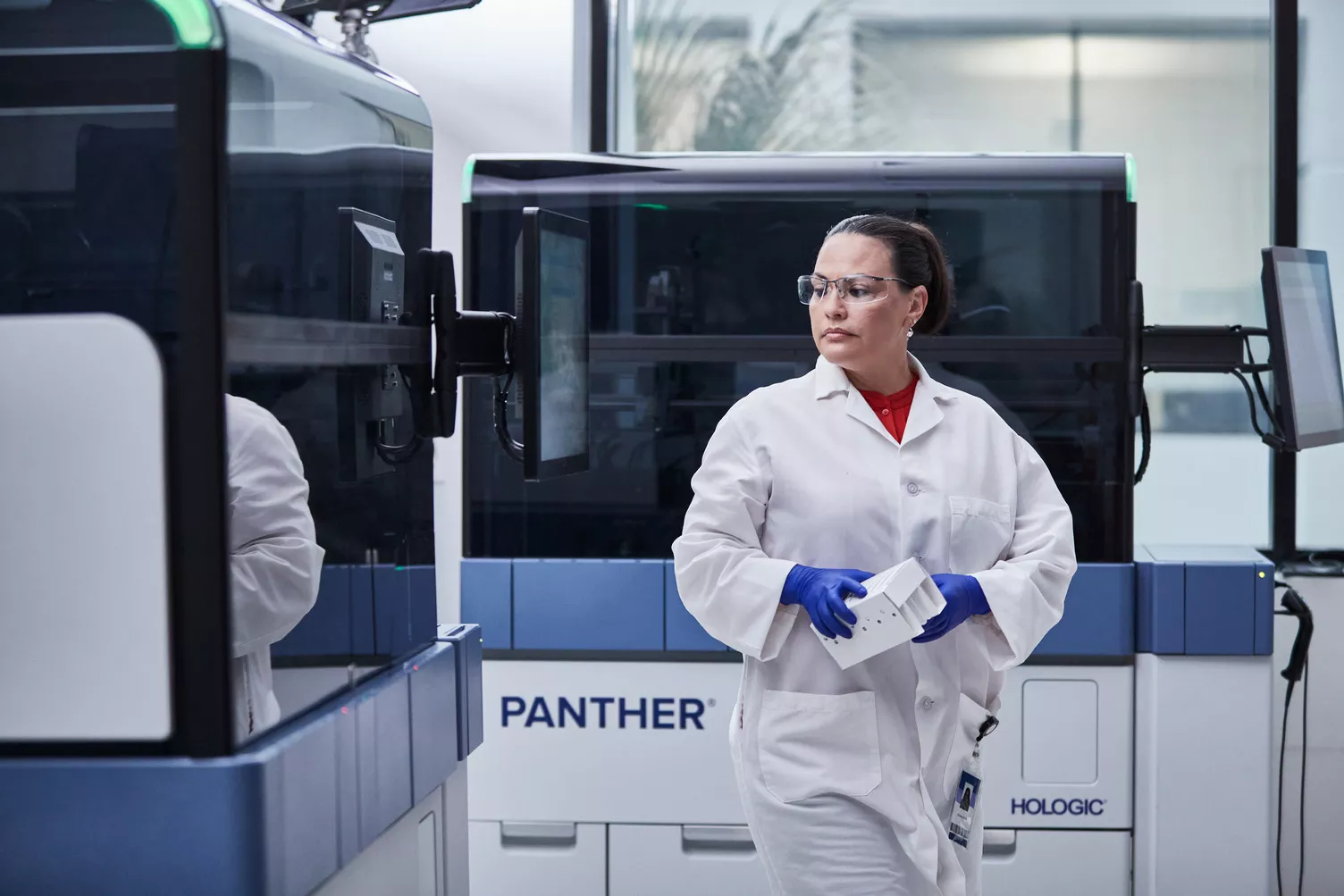 Technician walking in front of Panther Systems in a lab setting.